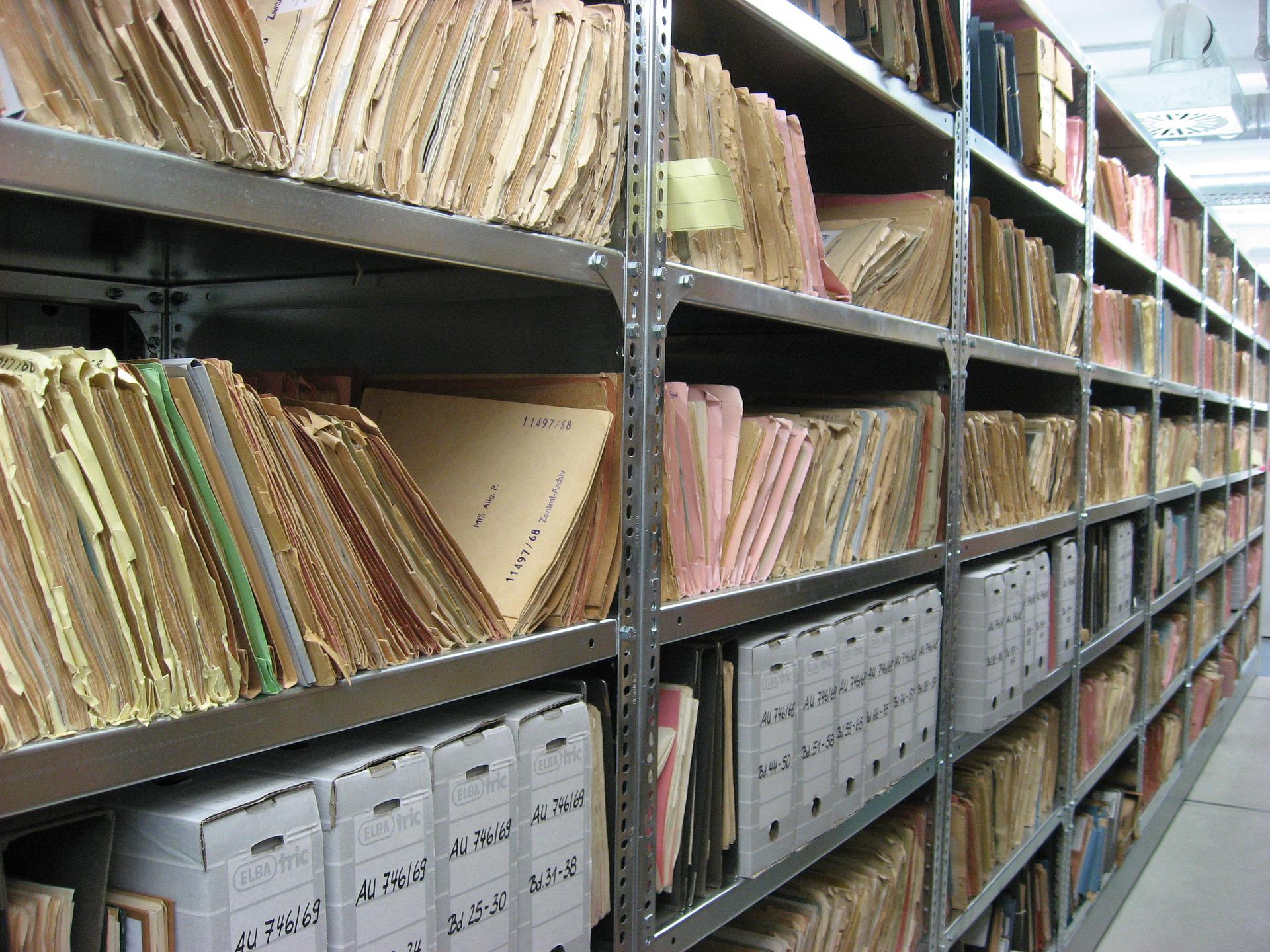 Old binders with files, standing in a row, partly stacked.
