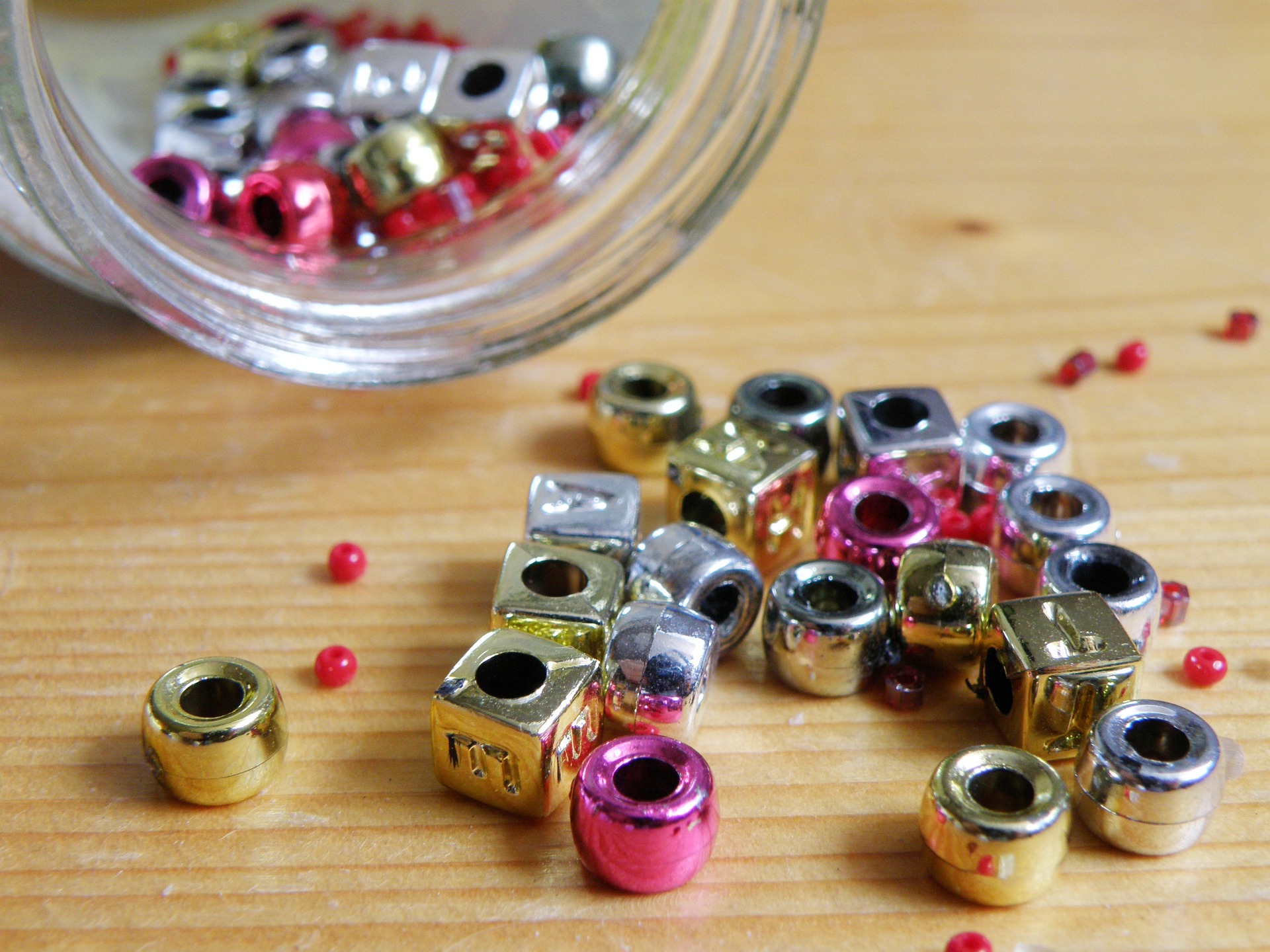 Beads in different colors and sizes spilling from a jar