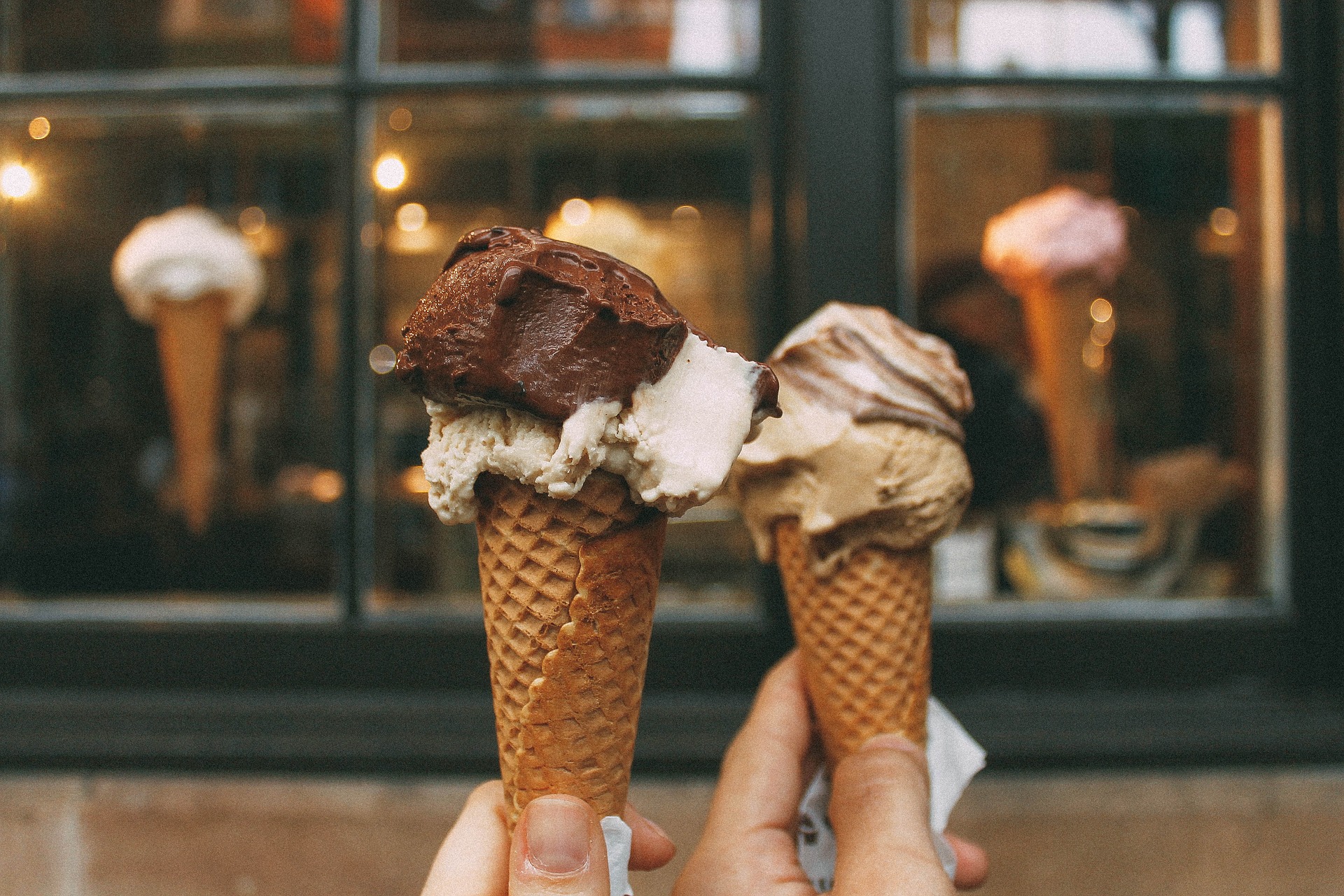 Two hands holding an ice cream cone each.