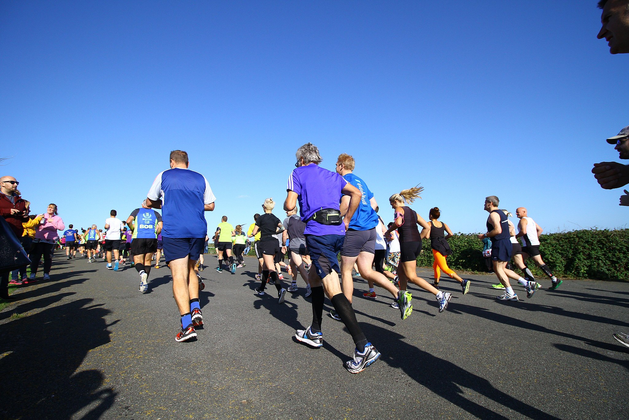 A marathon race in Kent. People running away from the camera. The sky is really blue.