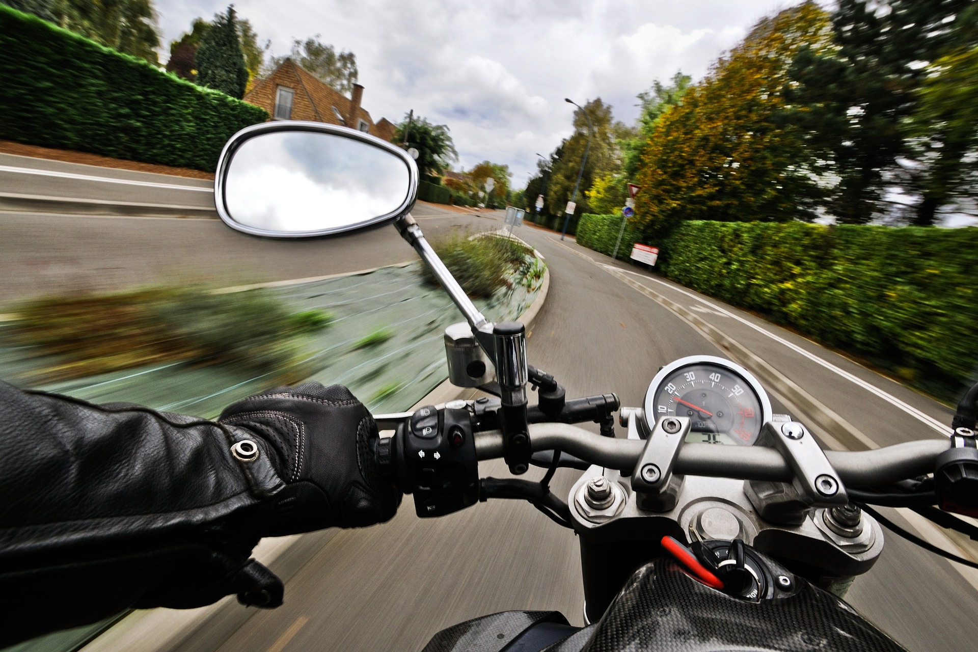 A rear view mirror of a motorbike going really fast.