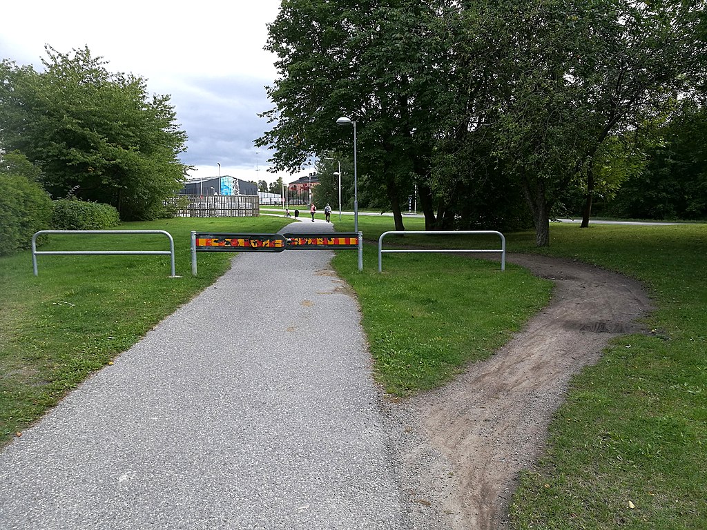 Bicycle traffic barrier used to slow down cyclists circumvented by taking a detour on the lawn, thereby showing a literal path of least resistance.