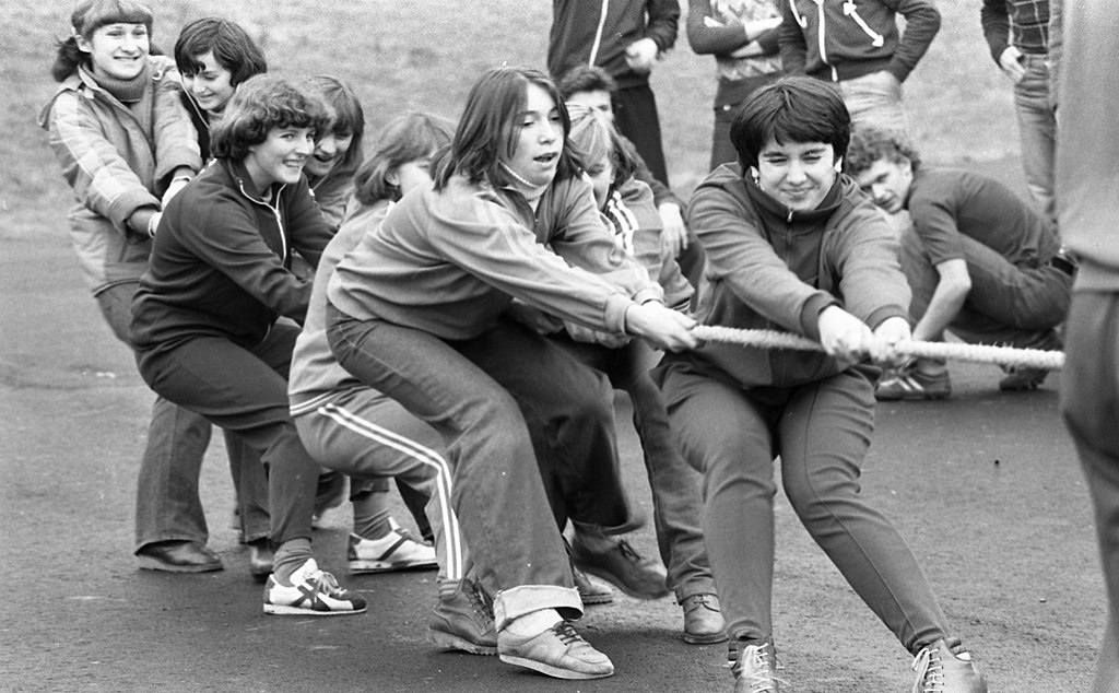 Black and white photo of a group of teens in 1978 pulling on one side of the rope in tug of wars.